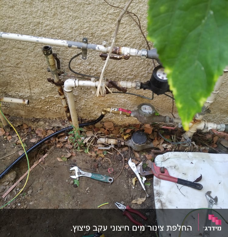 כלי עבודה של אינסטלטור ליד צנרת מים חיצונית
